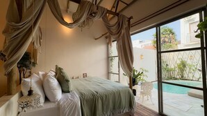 Un dormitorio con una cama grande, vistas a una piscina y un balcón con una silla.