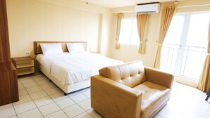 Een hotelkamer met een bed, een slaapbank, een nachtkastje en een raam met gordijnen.