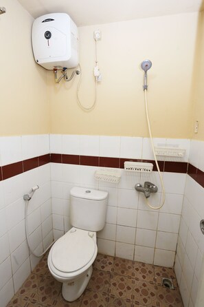 A small, tiled bathroom with a toilet, a showerhead, and a water heater.