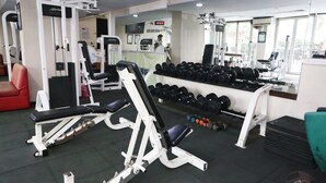 Een fitnessruimte met krachttrainingapparatuur, gewichten en cardioapparaten.