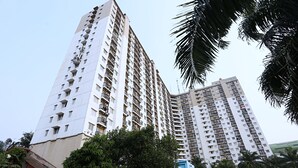 Een hoog appartementencomplex met meerdere balkons en een parkeerplaats ervoor.