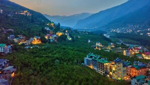 A mountainous town with buildings and a river. - Hotel Swastik Grand (Manali)