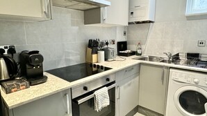 Cuina compacta amb fogó, forn i rentadora integrats.