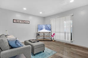 Relax in this inviting living space with a flat-screen TV, comfortable sofa, and a potted plant.