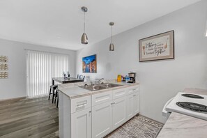 Enjoy cooking in this well-equipped kitchen with a central island, stainless steel sink, and dining area.