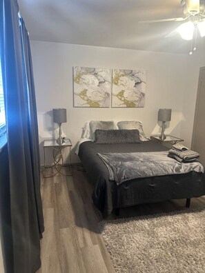 Cozy retreat with a central bed, ceiling fan, and wall-mounted lamps.