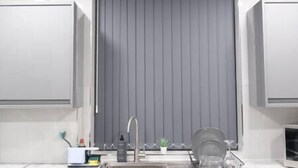 Una cocina moderna con una cortina gris, un lavamanos y un escurreplatos.