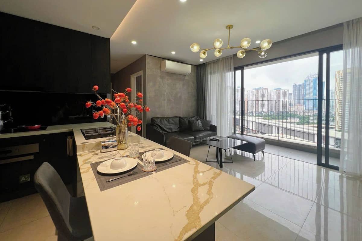 A modern living room with a dining area, a black leather sofa, a glass coffee table, and a view of the city through large windows.