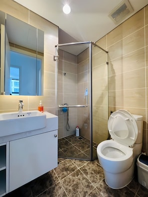 Un baño moderno con cabina de ducha, lavabo con espejo y retrete.