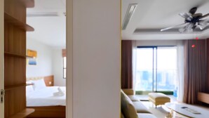 Ein Hotelzimmer mit Bett, Holzregalen, einer Couch, einem Couchtisch und einem Deckenventilator.