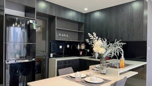 Eine moderne Küche mit integriertem Kühlschrank, dunklen Holzschränken und einem Essbereich mit einem Marmortisch.