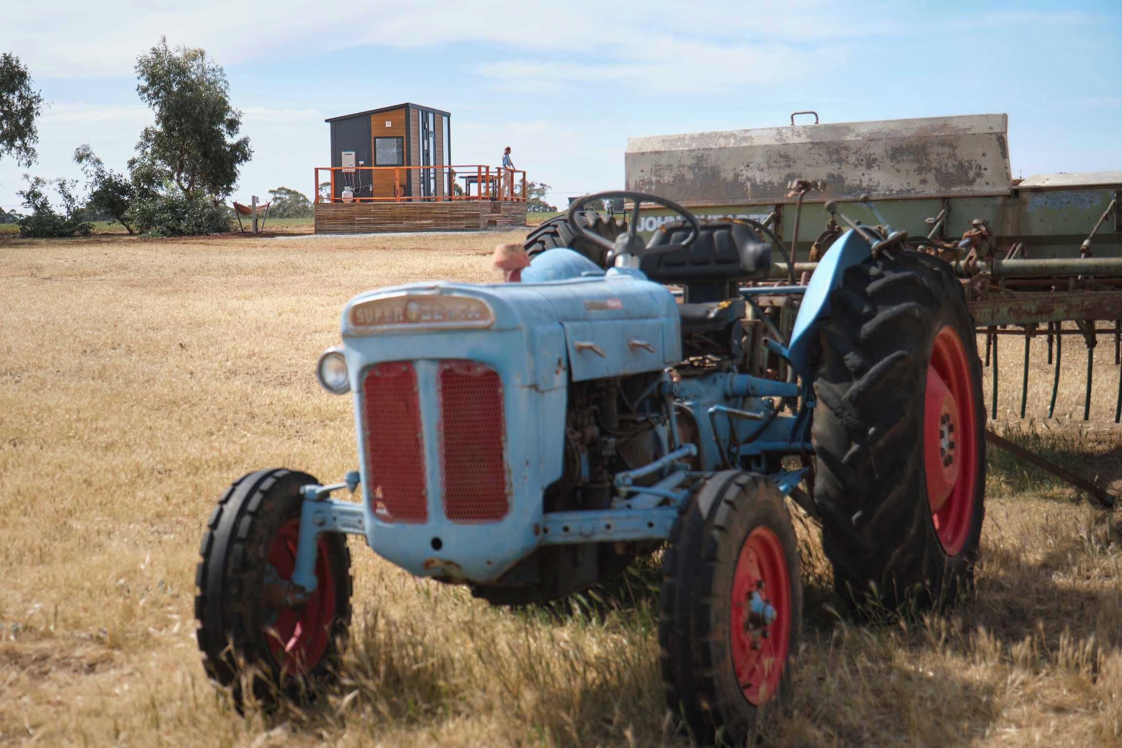 Un tractor azul con ruedas rojas en un campo.