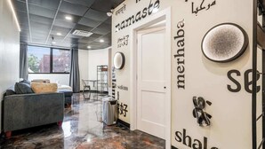 A modern lobby with a marble floor, a sofa, a trash bin, and a wall with text and a logo. - *New* Loft 7 min to Acrisure Stadium Sleeps 4 (Pittsburgh)