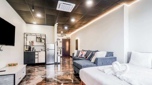 A modern hotel room with a large bed, a sofa, a small kitchen area, and a flat-screen TV. - *New* Loft 7 min to Acrisure Stadium Sleeps 4 (Pittsburgh)