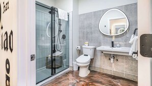A modern bathroom with a glass shower enclosure, a toilet, a sink with a mirror, and a marble floor. - *New* Loft 3 min to Local hospitals Sleeps 4 (Pittsburgh)