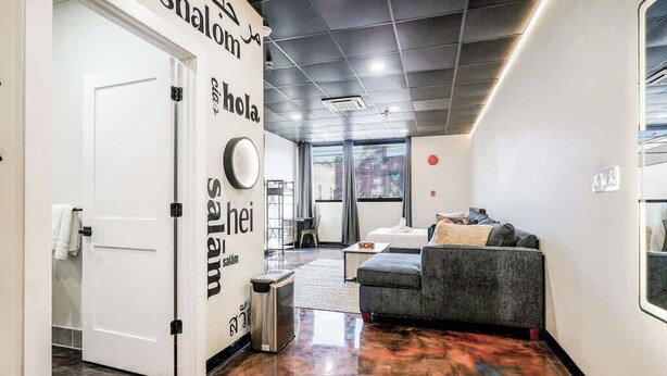 A modern lobby with a polished floor, a sofa, and a door leading to a bathroom.