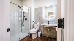 A modern bathroom with a glass shower enclosure, a toilet, and a sink with a mirror above it.