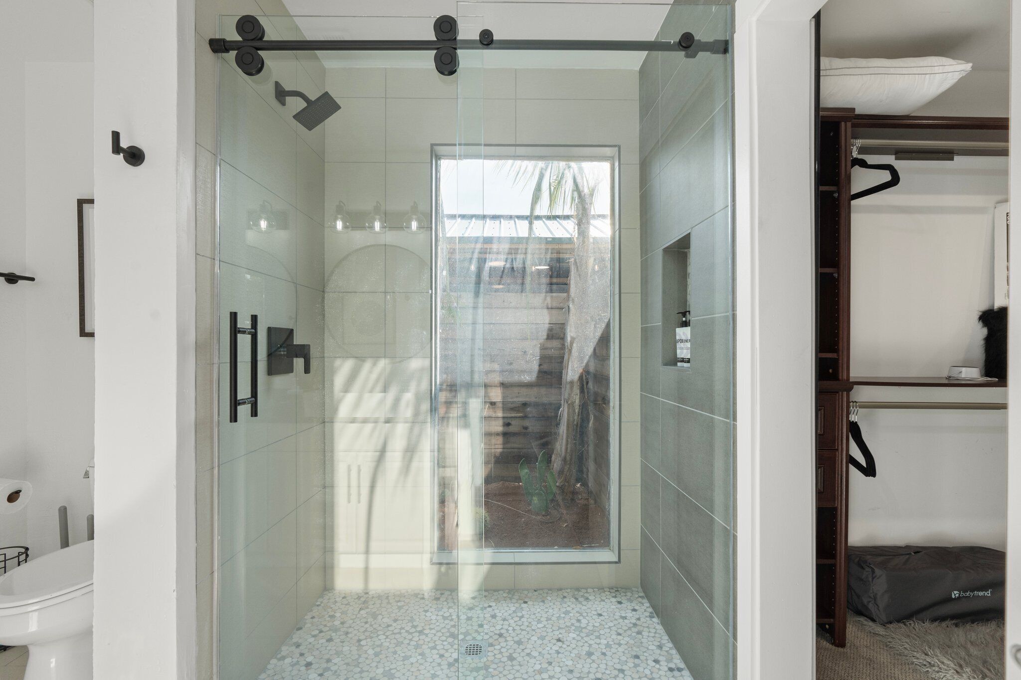 Une salle de bain moderne dotée d’une douche à parois de verre, de toilettes et d’un banc intégré avec espace de rangement.