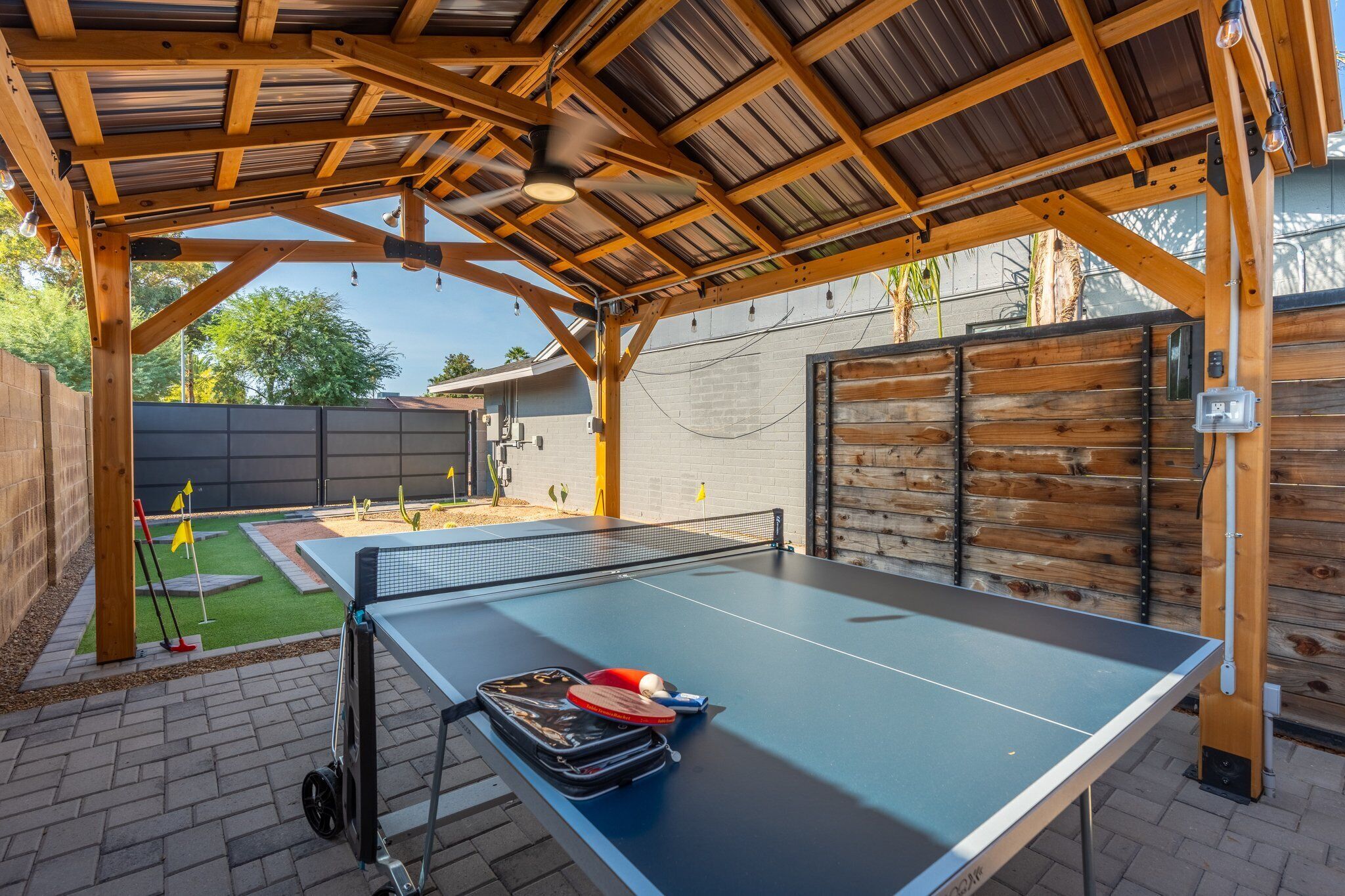 An outdoor ping pong table with a canopy, a golf cart, and a tennis ball.