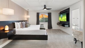 Et moderne hotelværelse med seng, fjernsyn, ventilator og et vindue med gardiner.