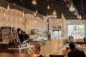 Ein Café-Interieur mit Theke, Sitzgelegenheiten und hängenden Lampen.