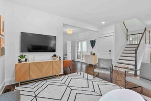 Relax in a spacious living area with a large flat-screen TV, comfortable sofa, and geometric-patterned rug.