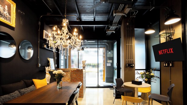 A modern dining area with a wooden table, chairs, and a chandelier.