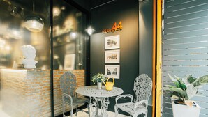 A room with a round table, four chairs, a potted plant, and a wall with framed pictures and a sign.