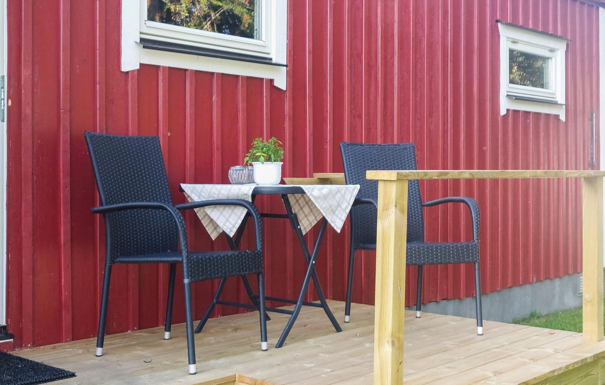 Un espace extérieur aménagé avec une table et deux chaises, un pot de fleurs et une terrasse en bois.
