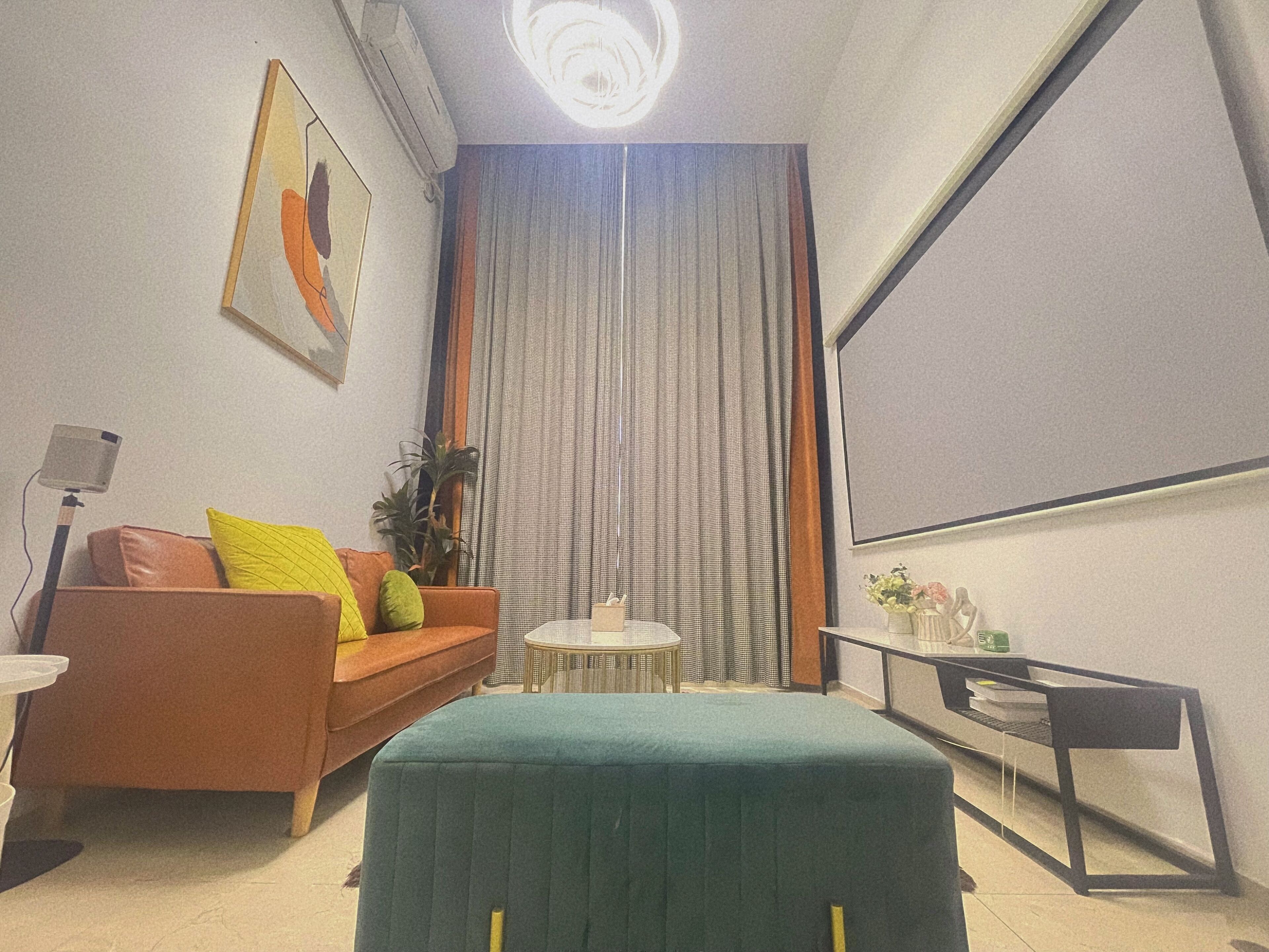A modern living room with a sofa, ottoman, and a small table.