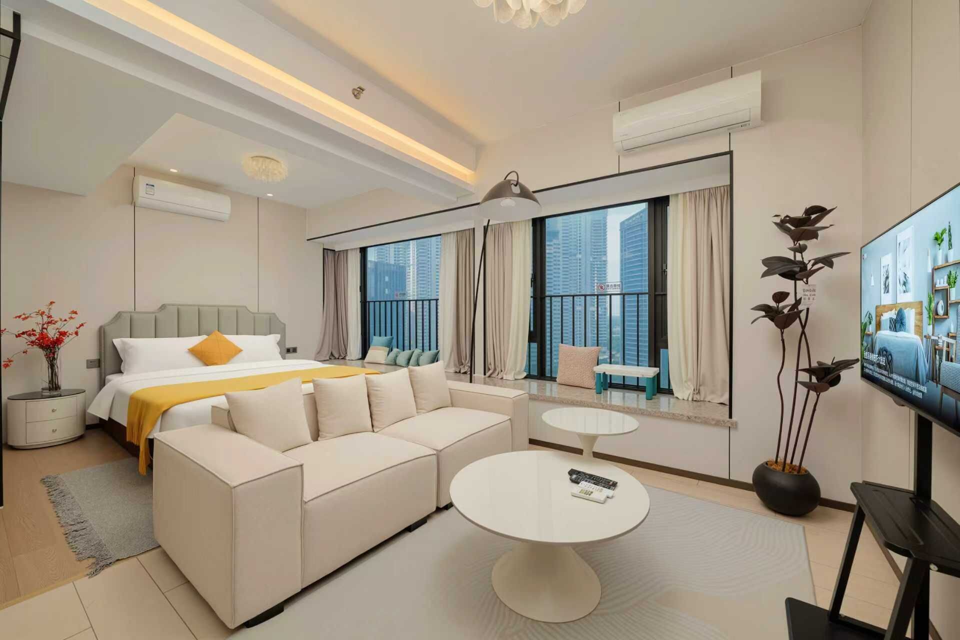 A modern hotel room with a large bed, a sofa, a round coffee table, and a TV.