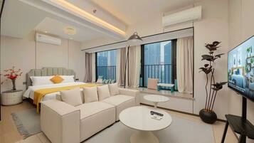 A modern hotel room with a large bed, a sofa, a round coffee table, and a TV.