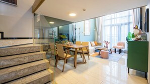 Una sala moderna con comedor, una escalera y un aparador verde.
