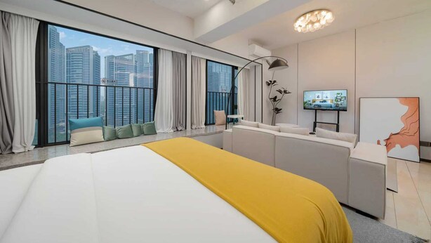 Habitación de hotel moderna con una cama grande, un escritorio, un televisor y un balcón con vistas a la ciudad.