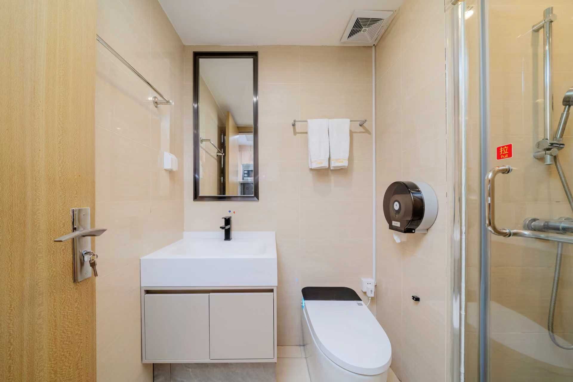 Un baño moderno con un lavabo blanco, un espejo, un inodoro y una cabina de ducha de vidrio.