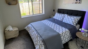 Un dormitorio con una cama, una ventana, un estante en la pared y un cuadro.