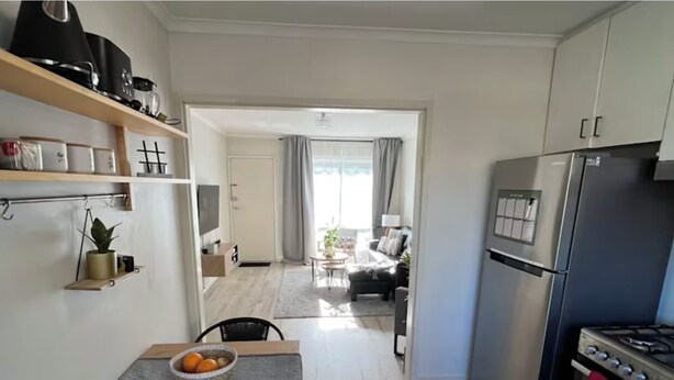 Una cocina moderna con estufa integrada, refrigerador y comedor con mesa y sillas.