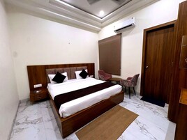 Un dormitorio con cama, mesitas de noche, escritorio, silla, aire acondicionado y armario.