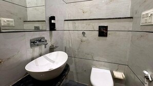 A modern bathroom with a large oval sink, a toilet, and a mirror. - Hotel Shrinath Palace (Mathura)