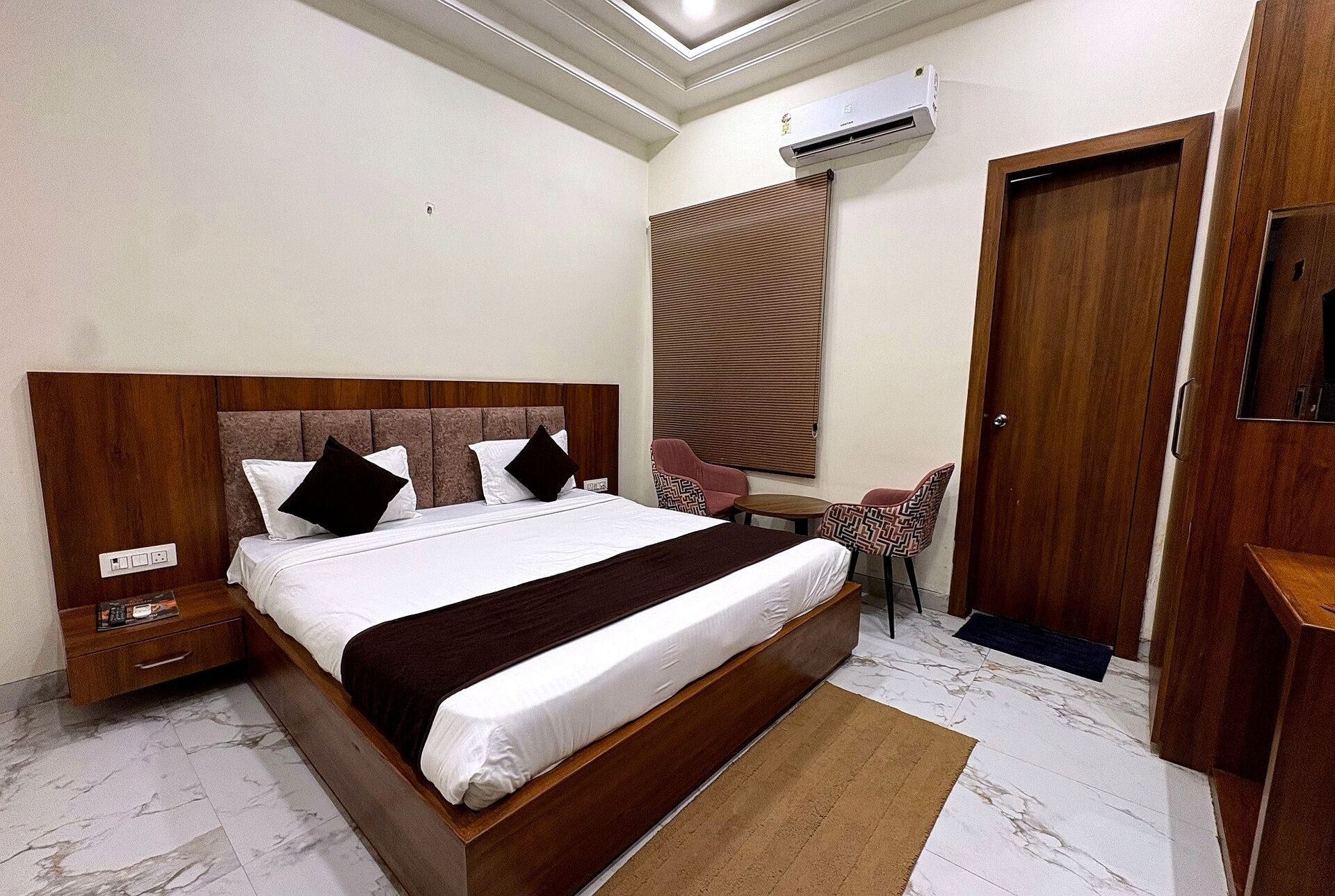 Una habitación de hotel con una cama grande, un escritorio, una silla, un armario y un equipo de aire acondicionado.