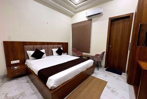 Una habitación de hotel con una cama grande, un escritorio, una silla, un armario y un equipo de aire acondicionado.
