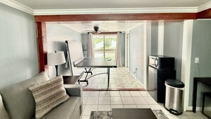 A living room with a sofa, a coffee table, a lamp, a whiteboard, and a ceiling fan.