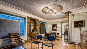 A room with a wooden floor, a leather chair, a blue chair, a table with a magazine, and a ceiling light fixture. - Historic Artist Home-Walk to SXSW+6th St+UT (Austin)