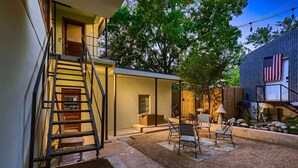 A modern house with a staircase leading to a second floor, a patio with outdoor furniture, and a large American flag on the side. - Historic Artist Home-Walk to SXSW+6th St+UT (Austin)