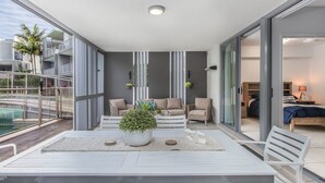 A modern living room with a white table, sofas, and a large potted plant.
