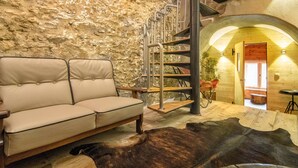 A cozy interior with a stone wall, a sofa, a staircase, and a cowhide rug. - Holiday home with a sauna near three ski resorts (Pfunds)