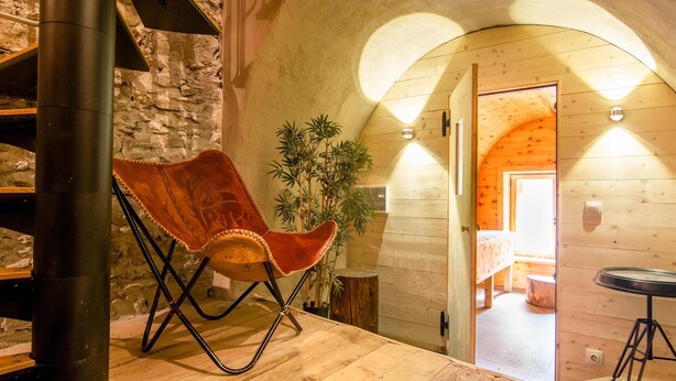 A cozy room with a wooden floor, a folding chair, a potted plant, and a staircase leading to another area. - Holiday home with a sauna near three ski resorts (Pfunds)