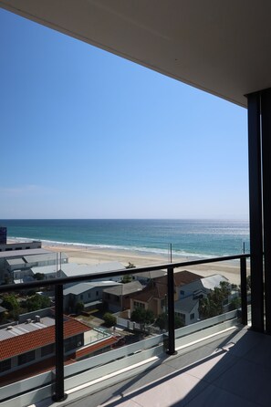 A balcony with a view of the beach and ocean.