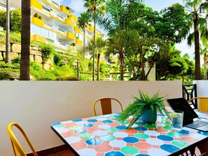 A table with a colorful tiled top, a laptop, a glass of water, and a potted plant. - Calanova Grand Golf stunning apartment (Mijas Costa)