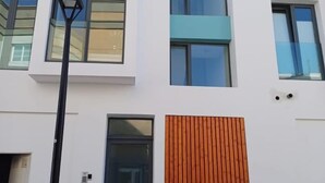 Un edificio moderno con múltiples ventanas y un panel de madera en la fachada.